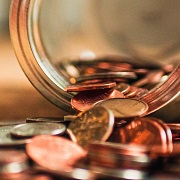 Jar lays sideways on a table with coins spilling out of it.