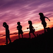 Silhouettes of several children playing outside in the evening.