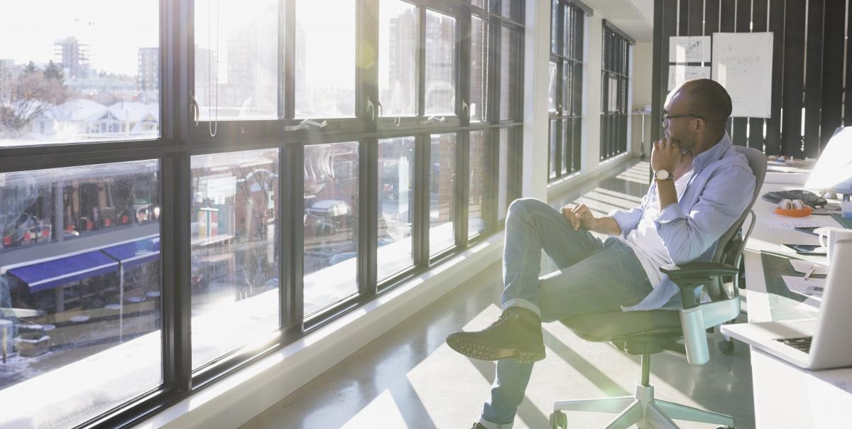 Contemplative professional in conference room looking out onto cityscape.