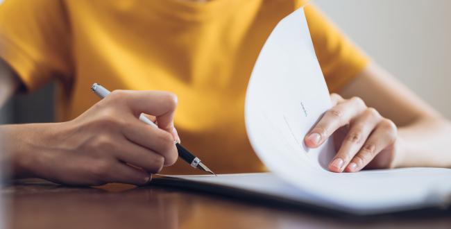 Person signing a paper document with a pen
