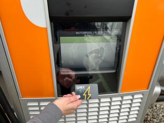 A WEX card taps it to the screen to pay for their EV charging bill.