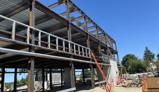 The Pritchard Building project as of July 8, 2025. The building's skeletal structure is showing and a user can see through the structure frame of exposed beams.