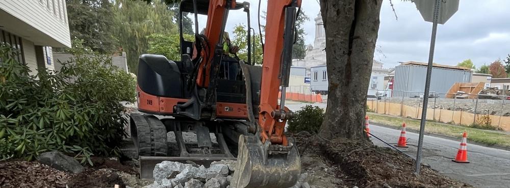 A bucket loader rips up sidewalk during construction