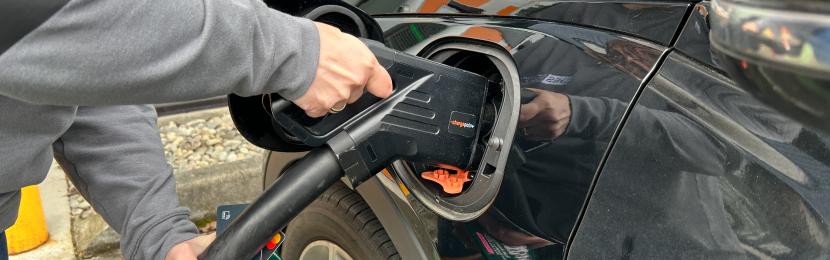 A driver plugs in an electric vehicle to a charging station