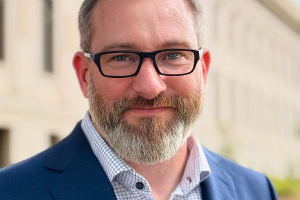 Matt Jones in a blue suite jacket and wearing glasses.